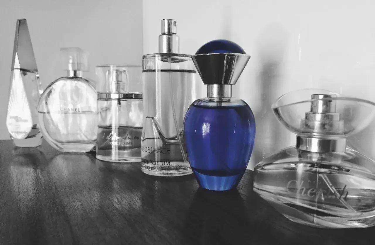 Rząd flakonów perfum, w tym Chanel i niebieski flakon, budzi pytanie: czy perfumy są szkodliwe?