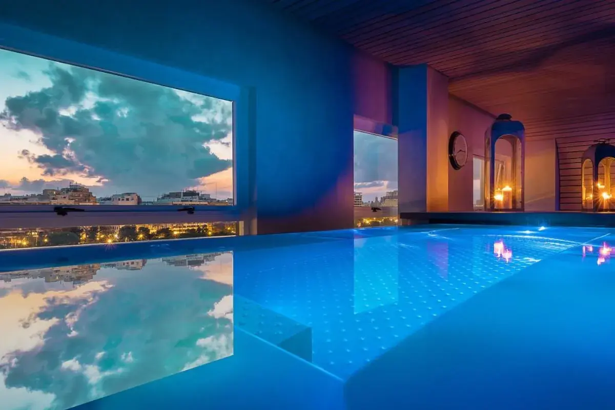 Piscina iluminada con vistas al atardecer de la ciudad. Un lugar perfecto para un día de spa en Valencia.