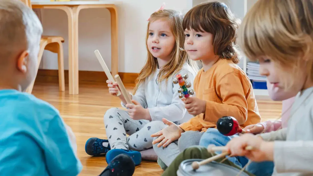 Kinder in der Kita lauschen gespannt einer Klanggeschichte und spielen mit Instrumenten.