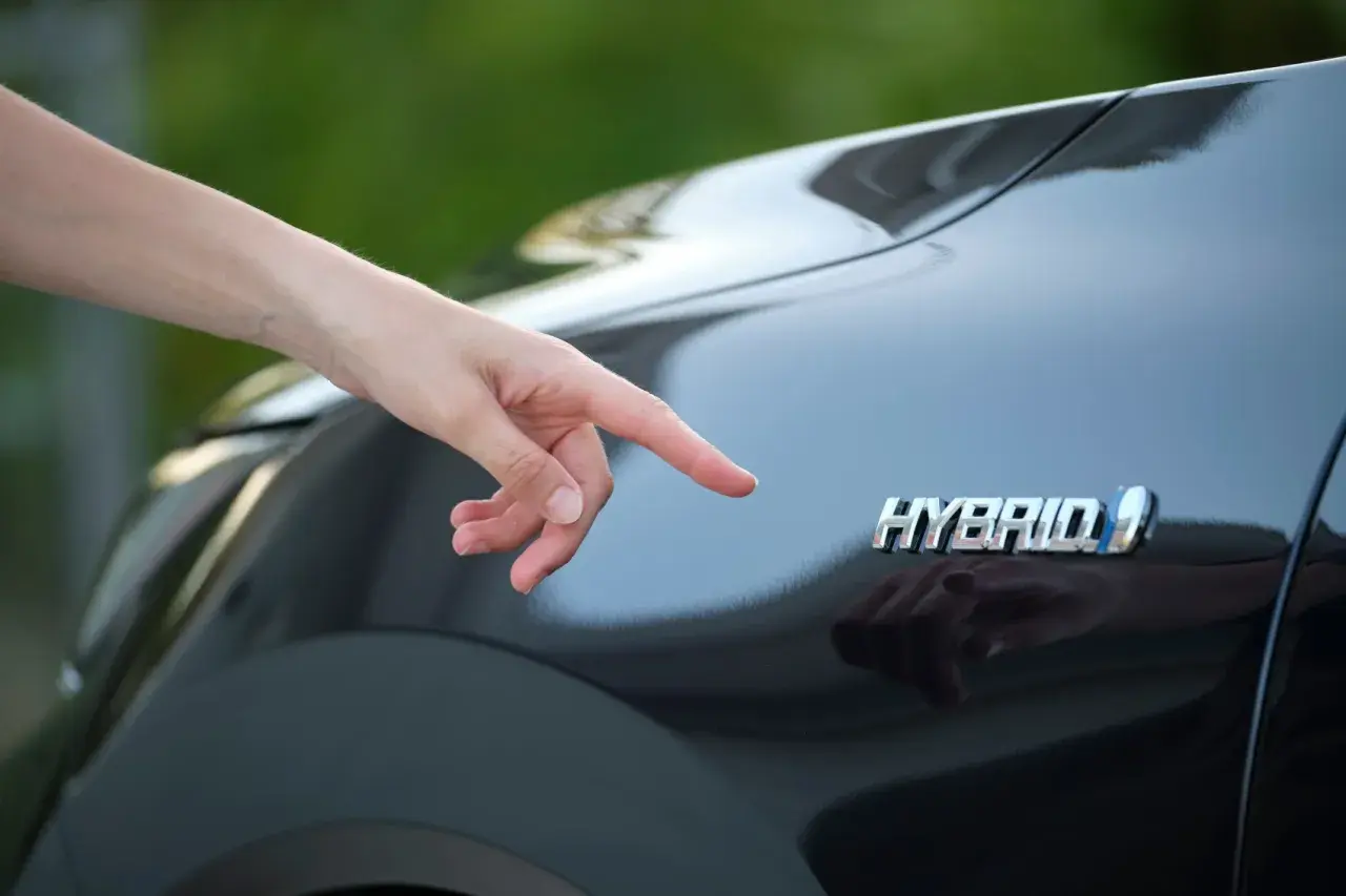 Dito il logo "Hybrid" su una Toyota Yaris. Si pensa al costo del bollo per un'auto ibrida.