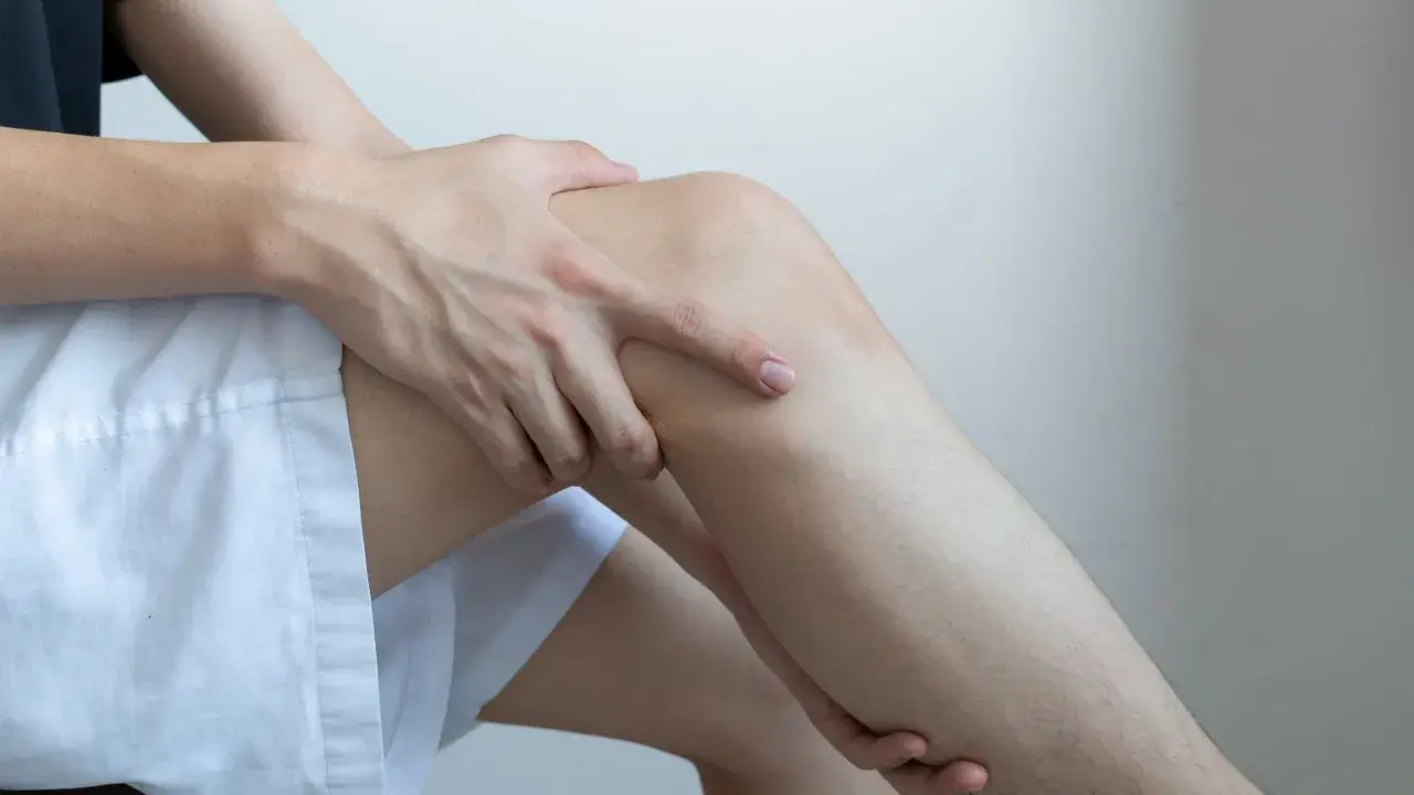 Dłoń uciska udo, sugerując ból lub dyskomfort, który może być jednym z niedobór potasu objawy neurologiczne.