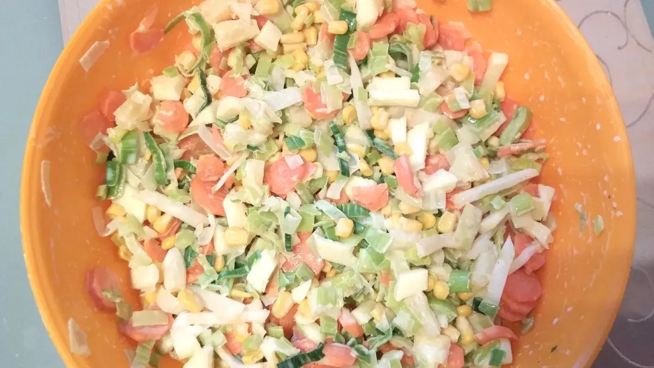Bunter Salat mit Porree, Karotten und Mais in einer orangen Schüssel. Ein frischer Genuss!