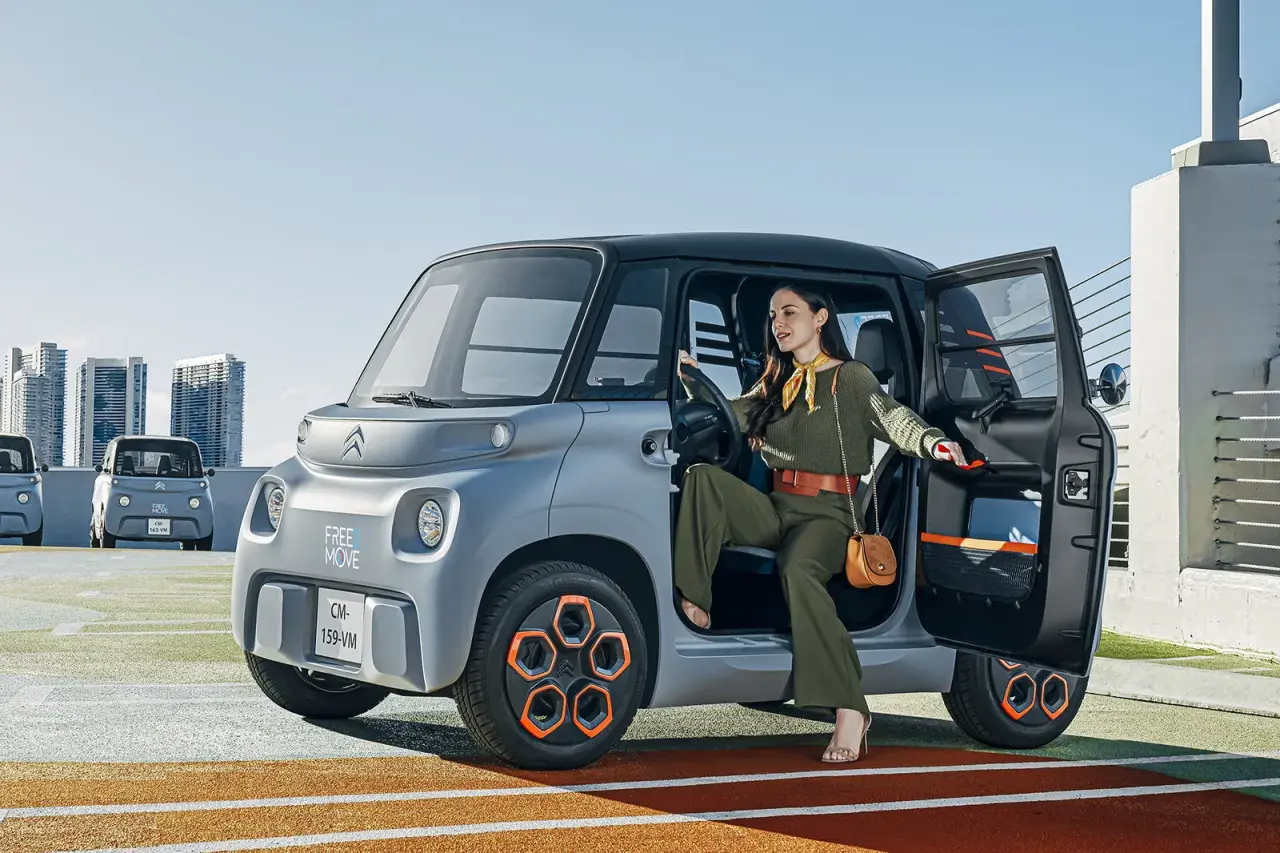 Donna scende da una Citroën Ami, un veicolo elettrico compatto. Le sue prestazioni sono ideali per la città.