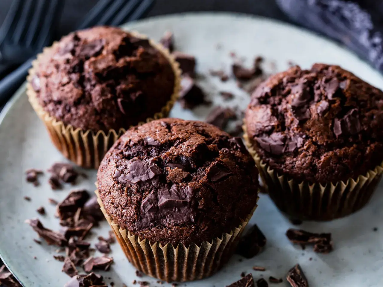 Drei saftige Schoko-Muffins mit Schokostückchen, perfekt für ein schnelles Muffins Rezept.