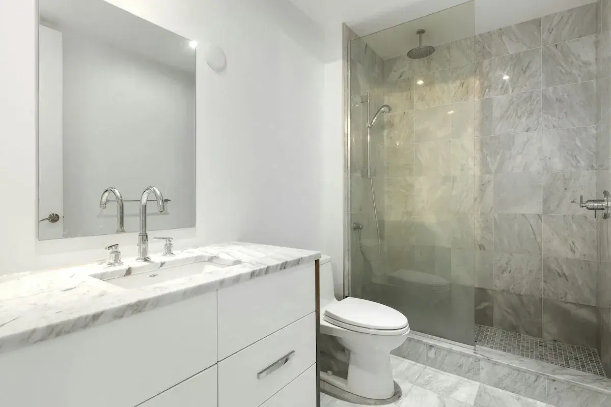 Modernt badrum med marmor, dusch och toalett. Enkel design som visar att det går att renovera badrum billigt med stil.