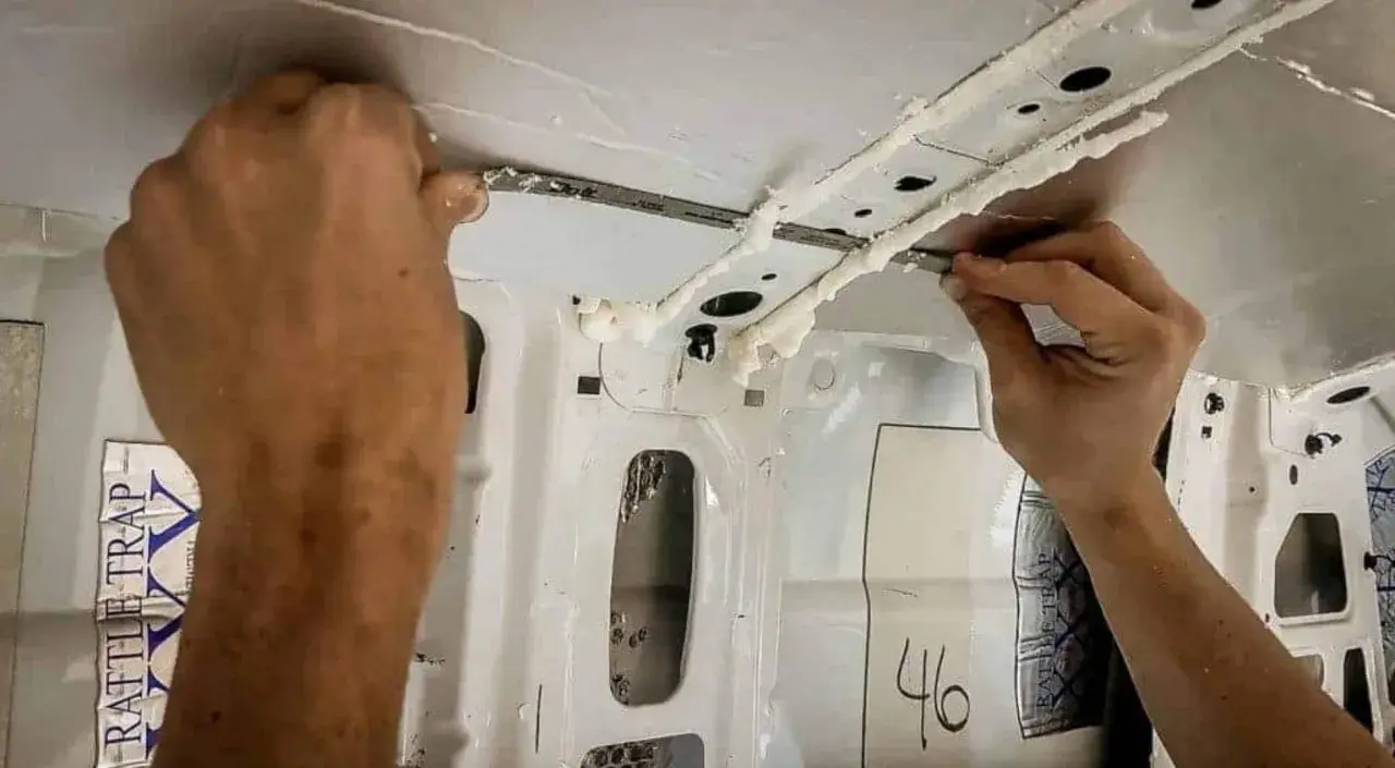 Application de mousse isolante sur la structure intérieure d'un fourgon, étape clé du plan camping-car.