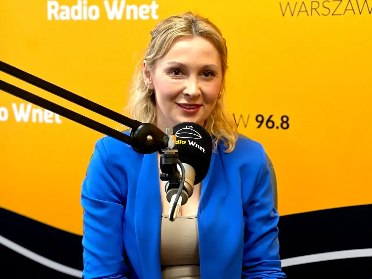 Joanna Miziołek, w wieku około 40 lat, w niebieskiej marynarce, przed mikrofonem Radia Wnet.