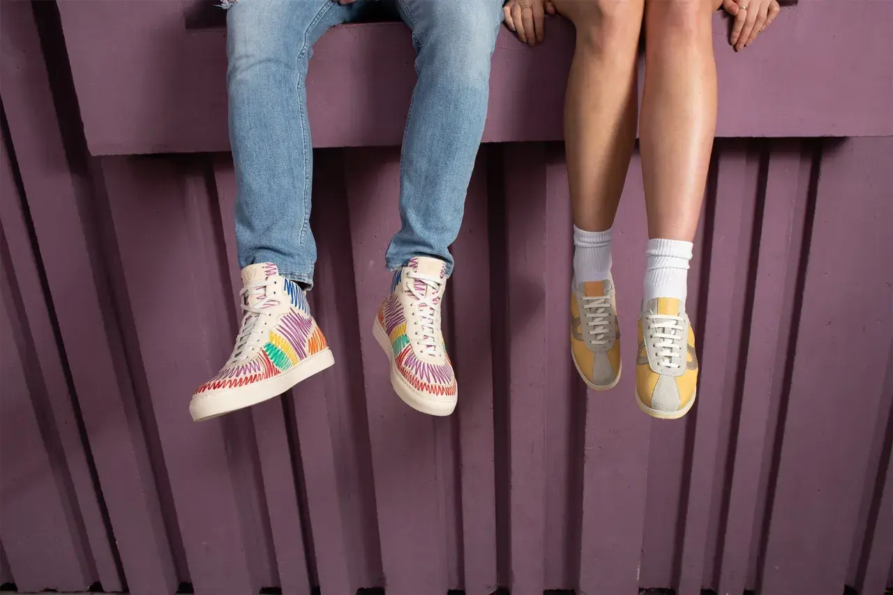 Kolorowe buty sneakersy i żółte, klasyczne sneakersy na nogach siedzących osób.