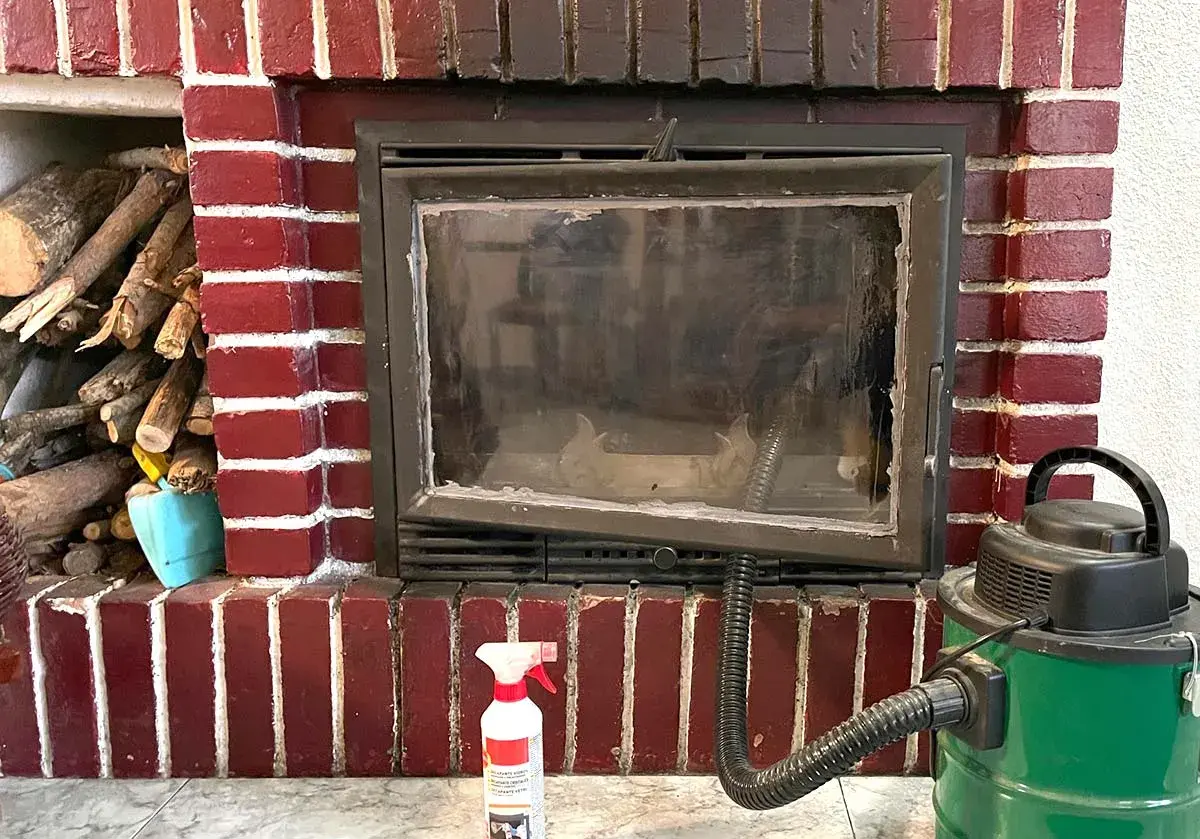 Preparativos para como deshollinar una chimenea: leña, aspiradora y spray limpiador.