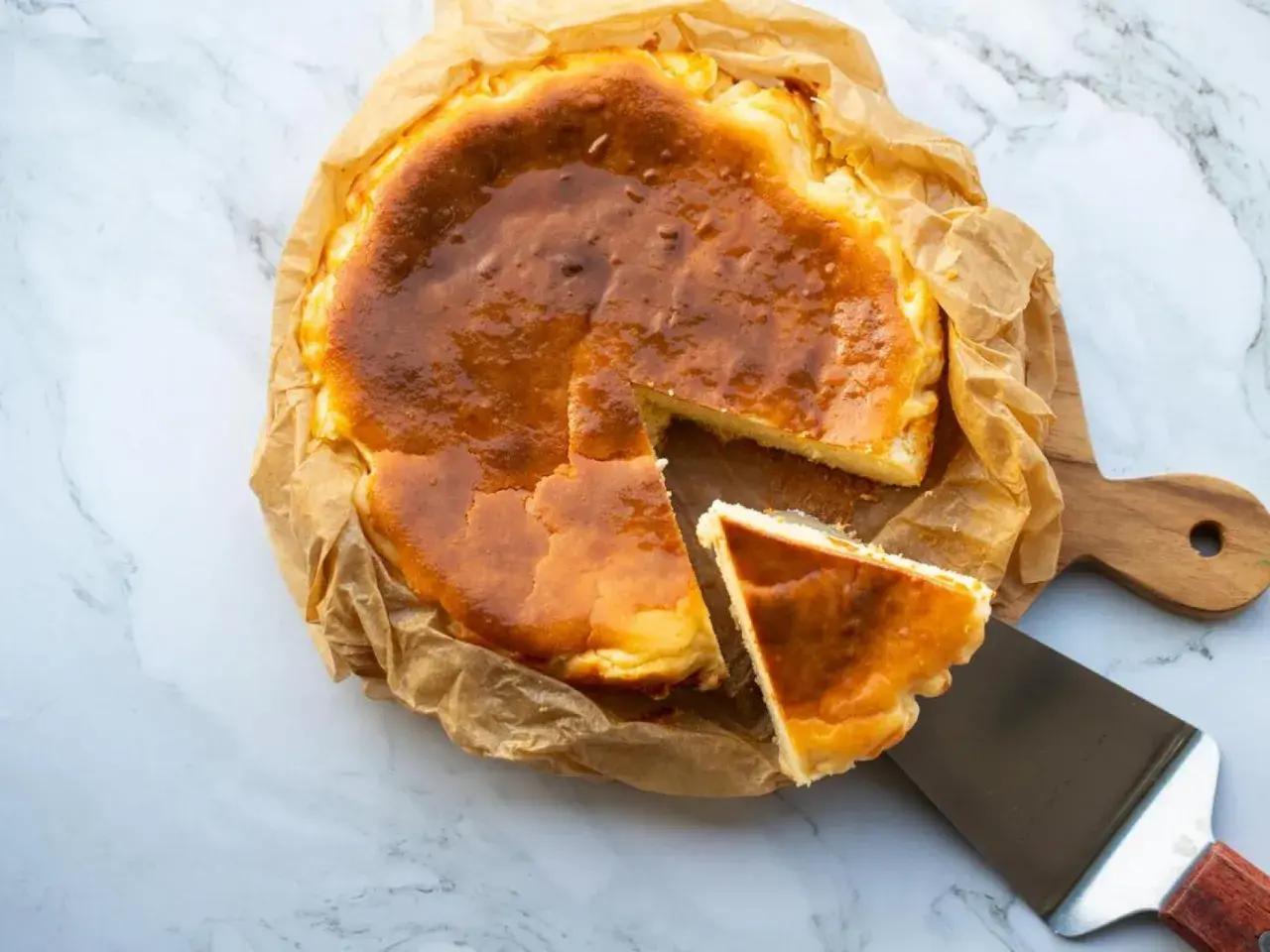 Tarta de queso congelada, dorada y cremosa, con una porción servida en una espátula.