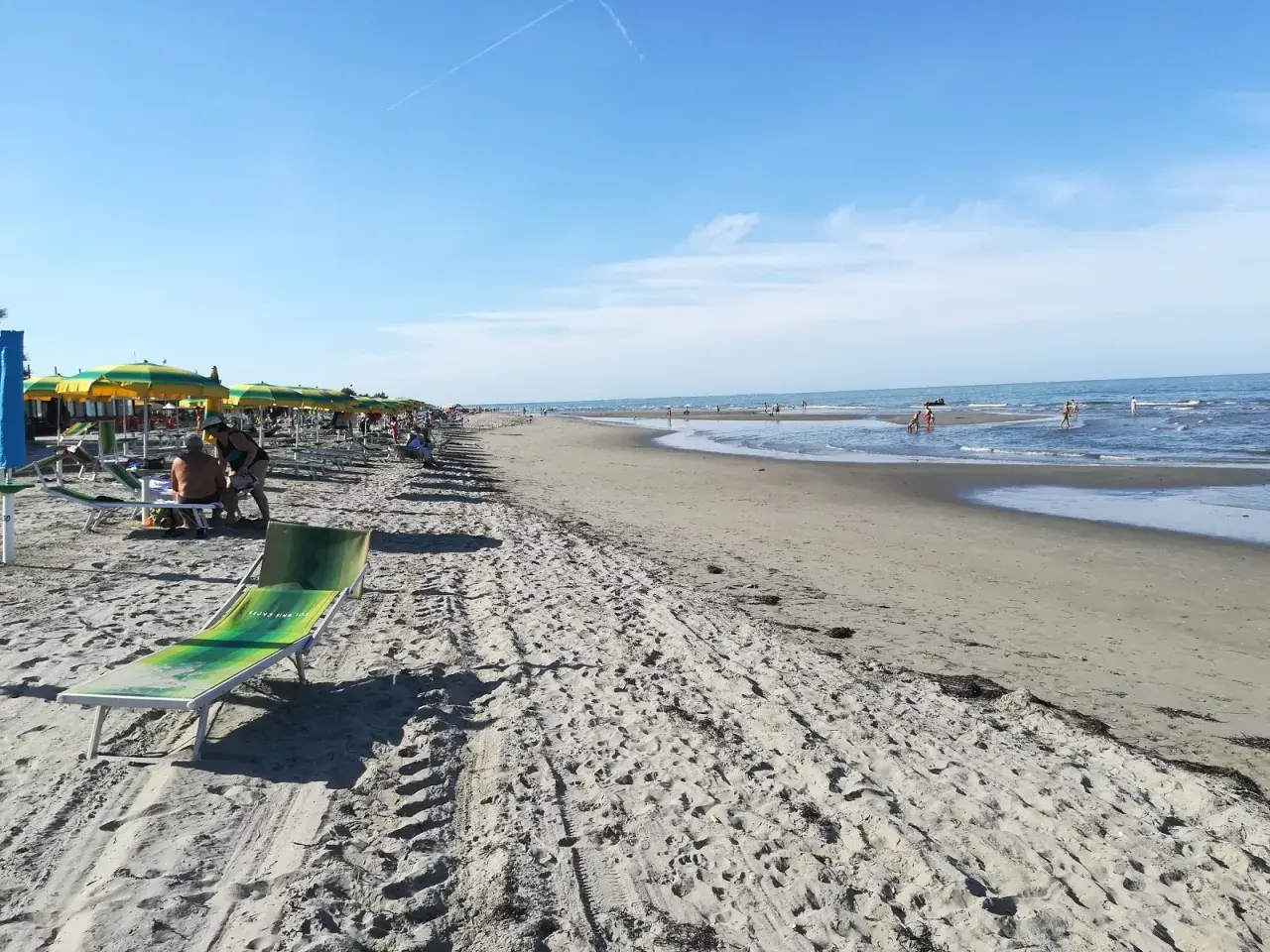 Una giornata di sole sulla spiaggia del Veneto. Ombrelloni colorati, lettini e il mare azzurro invitano al relax.