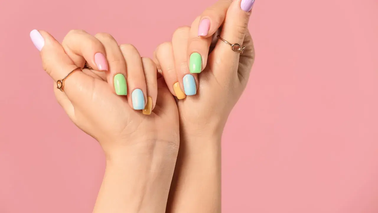 Dłonie z pastelowymi paznokciami, które pokazują, jak szybko rosną paznokcie u rąk.