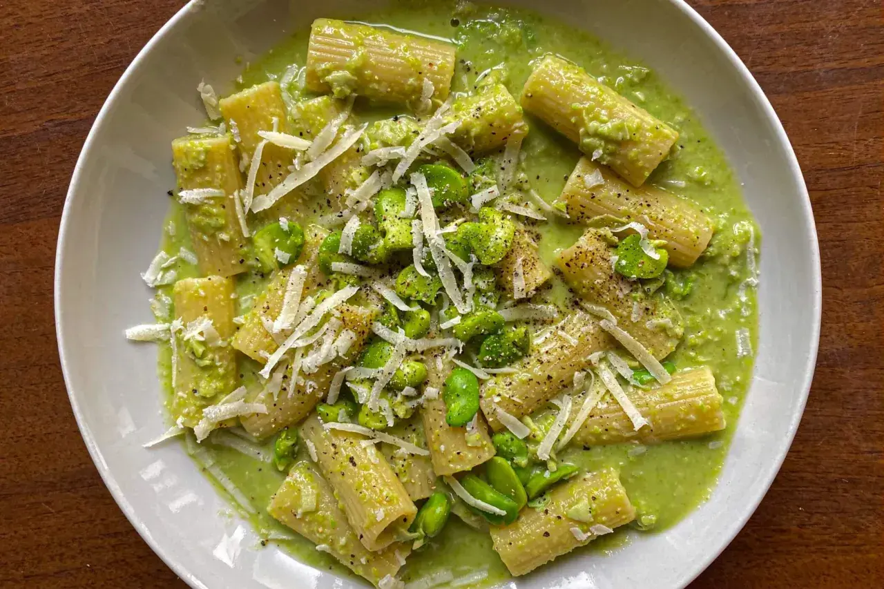 Piatto di pasta con fave fresche, crema verde e scaglie di pecorino. Un primo piatto primaverile invitante.