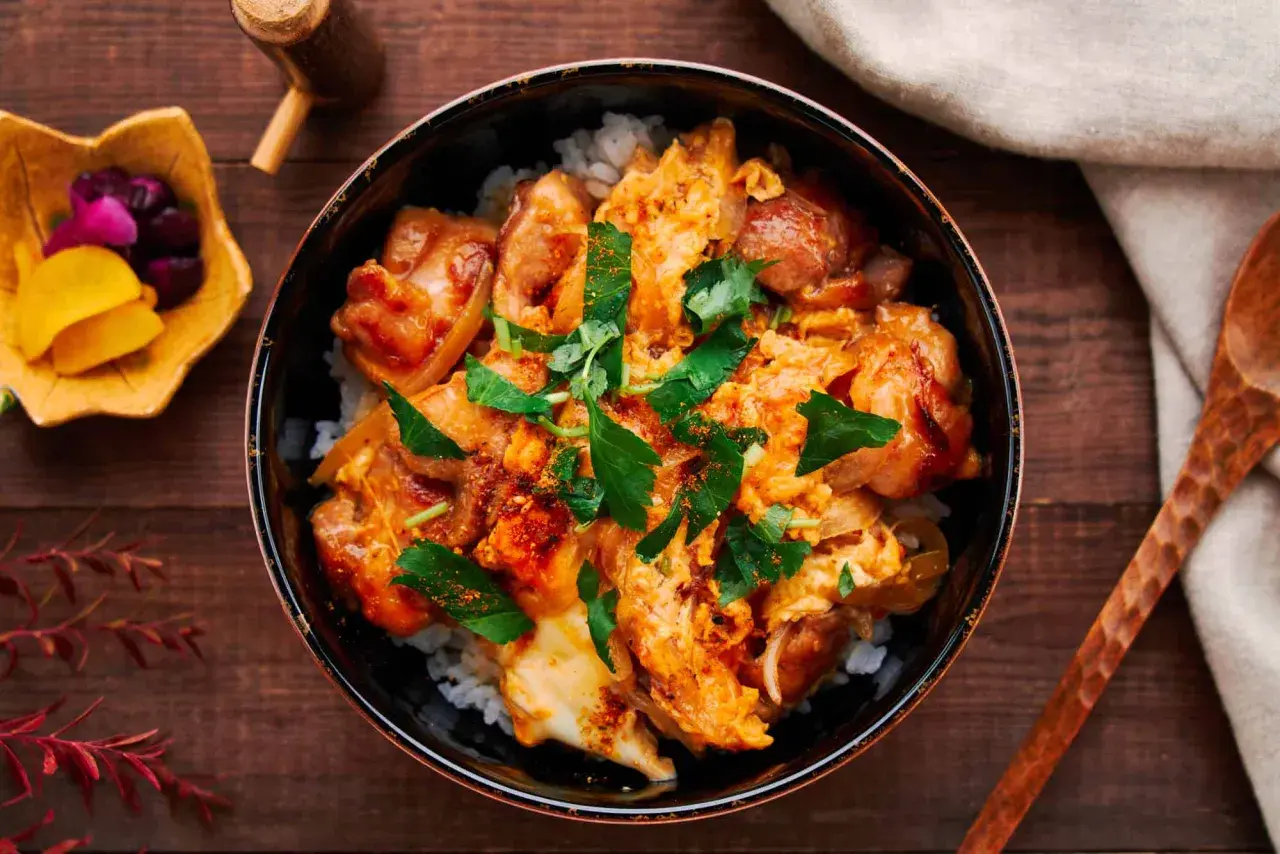 A delicious oyaku donburi recipe, featuring tender chicken and fluffy egg over rice, garnished with fresh parsley.