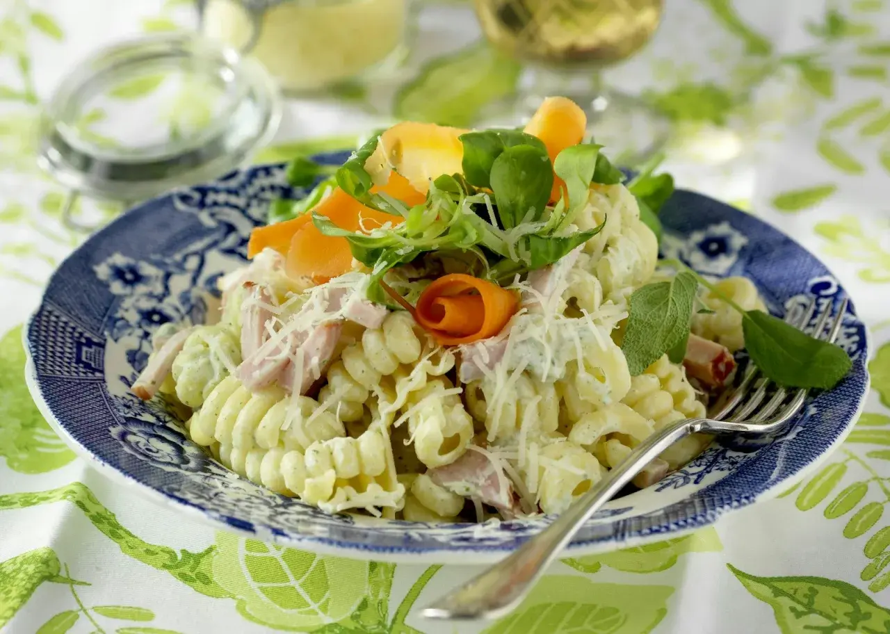 En härlig god pasta sallad med skinka, morötter och örter, toppad med riven ost. Perfekt för en lätt lunch eller middag.