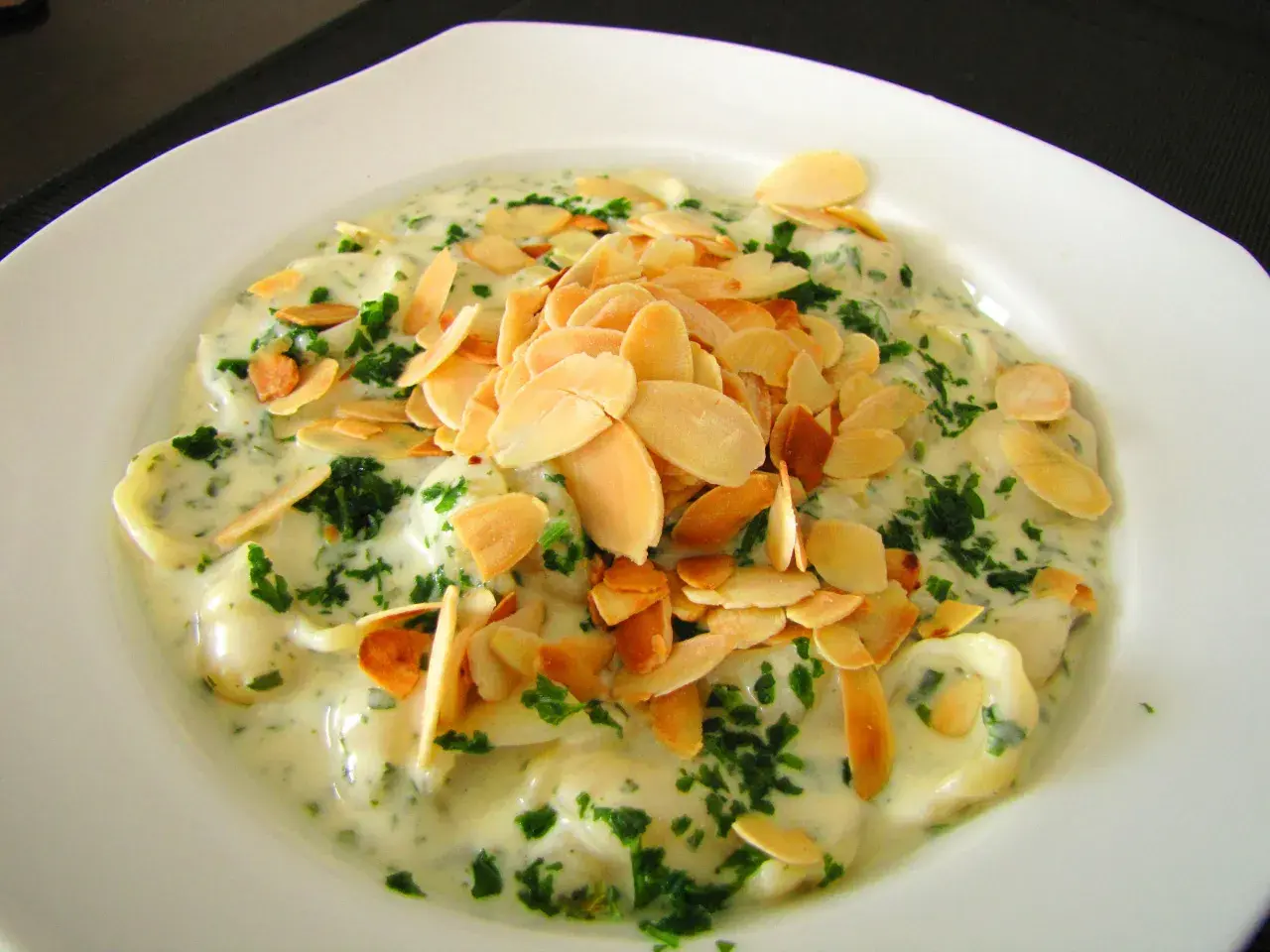 Ravioli w kremowym sosie z gorgonzolą, posypane płatkami migdałów i natką pietruszki. Idealne na wykwintne gorgonzola przepisy.