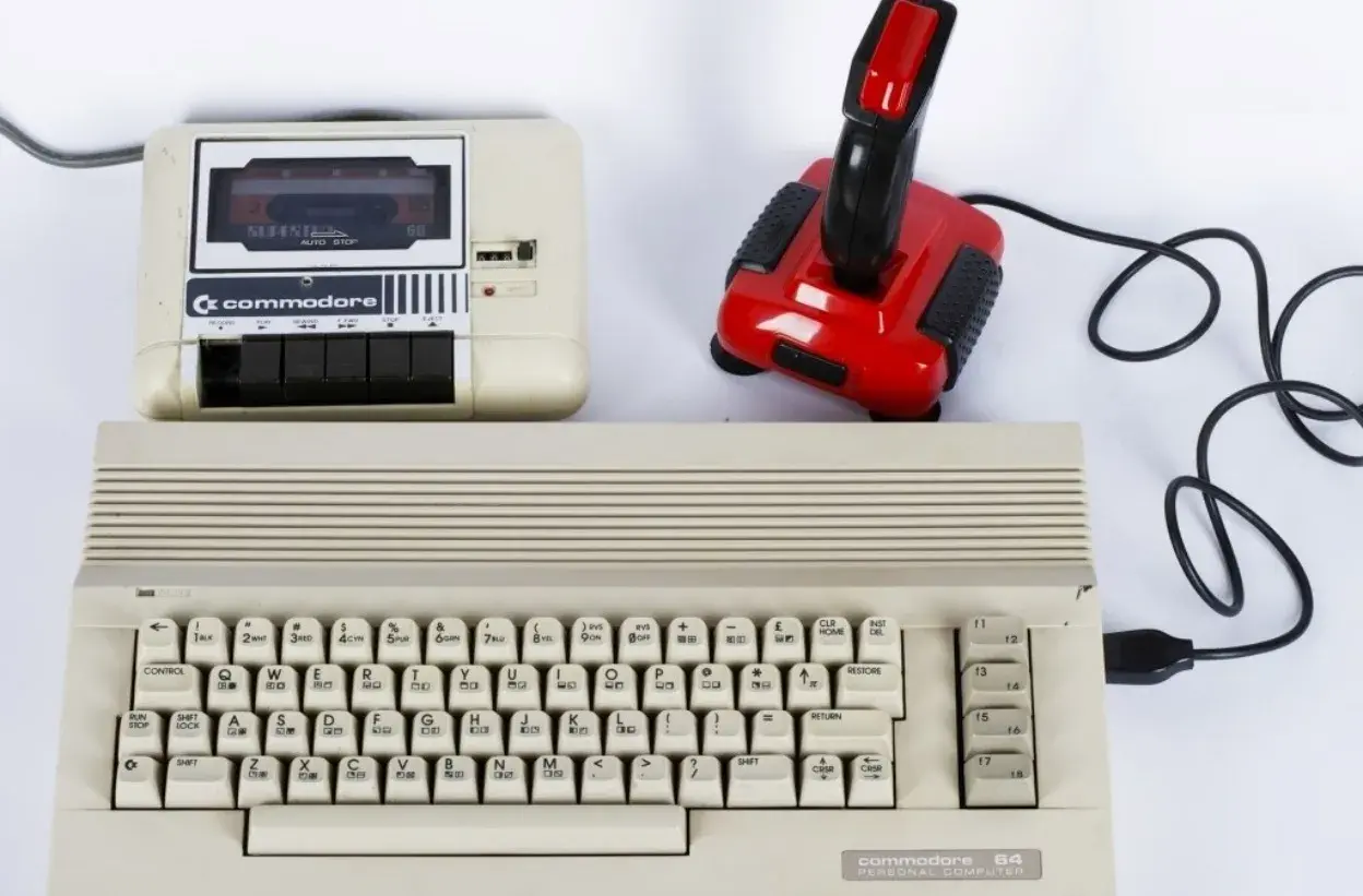 Commodore 64 z magnetofonem i joystickiem, idealny do tworzenia muzyki elektronicznej lat 80. zespoły.