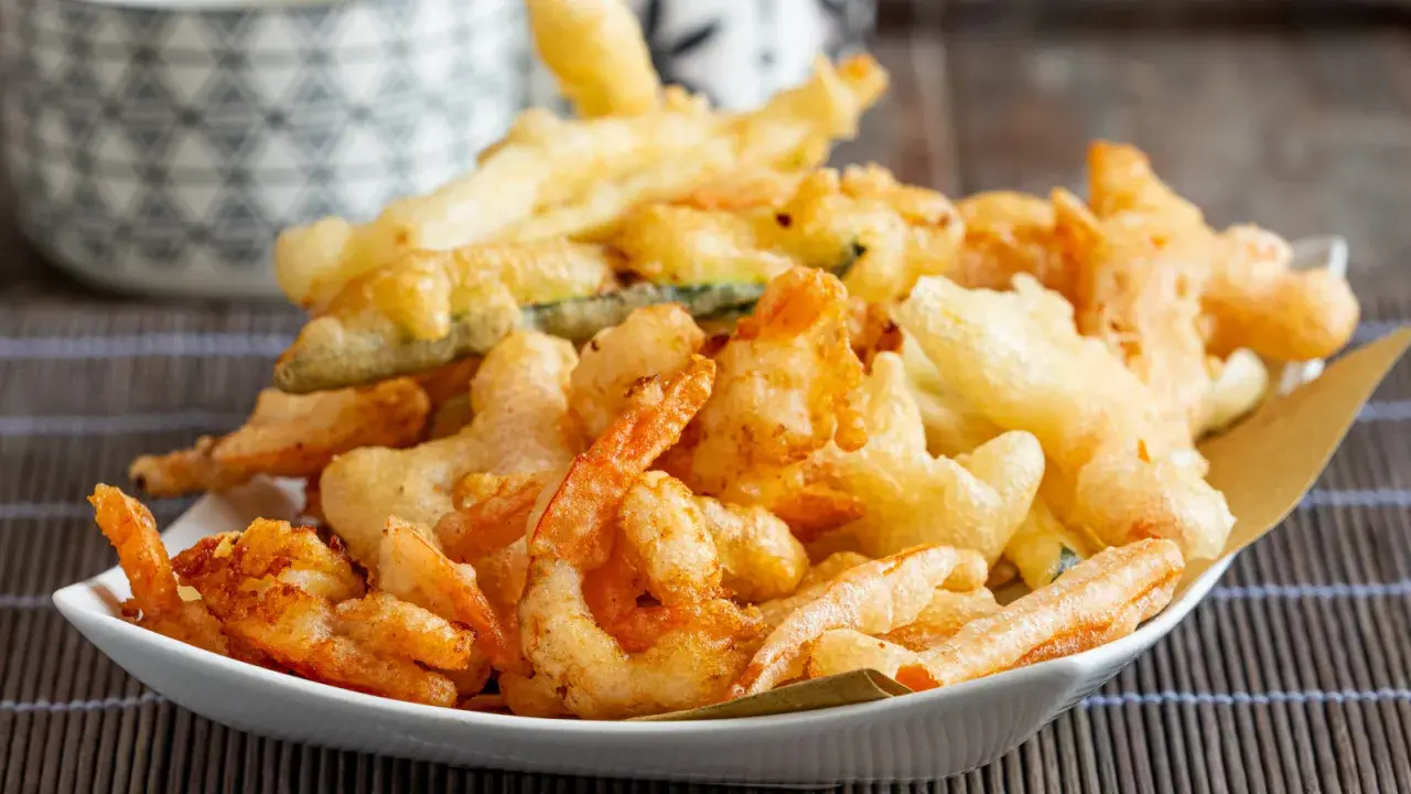 Un piatto invitante di gamberi in tempura dorati e croccanti, accompagnati da verdure fritte.