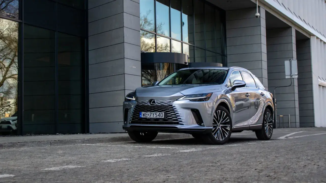 Elegancki, srebrny Lexus RX 350h zaparkowany przed nowoczesnym budynkiem z przeszkloną fasadą.