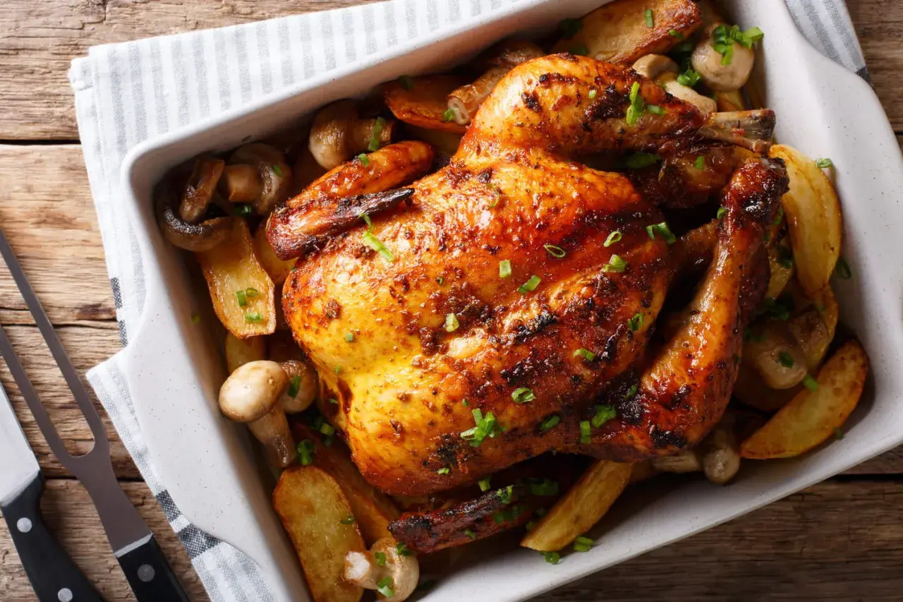 Un délicieux poulet au four, doré et croustillant, servi avec des pommes de terre rôties et des champignons.