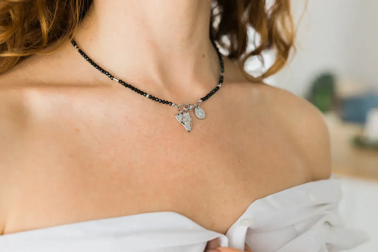 Delikatny choker z czarnych koralików i zawieszkami, podkreślający subtelność. Co oznacza choker na szyi? To ozdoba, która dodaje elegancji.