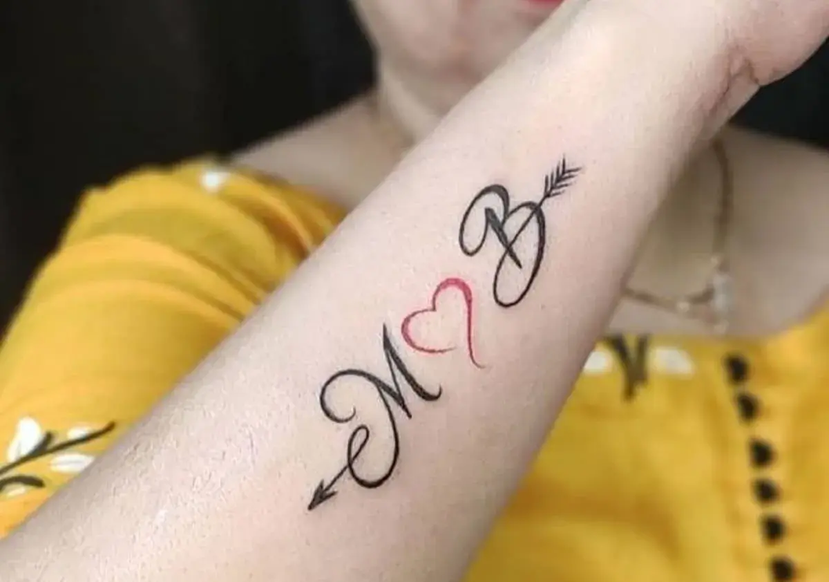 Tatuaż serce z inicjałami M i B, połączone strzałą. Symbol miłości i więzi.