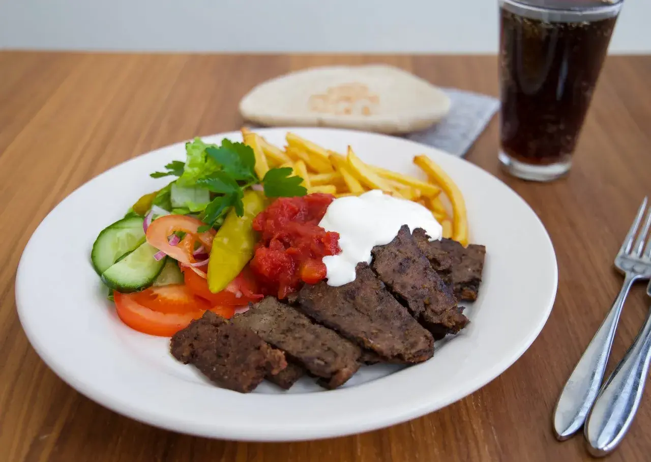 En tallrik med turkisk kebab från Zeinas Kitchen, med pommes frites, sallad, tomatsås och vit sås.