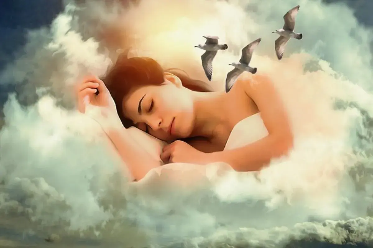 Una mujer duerme rodeada de nubes, con gaviotas volando. Es como soñar con mi abuela fallecida, un dulce reencuentro celestial.
