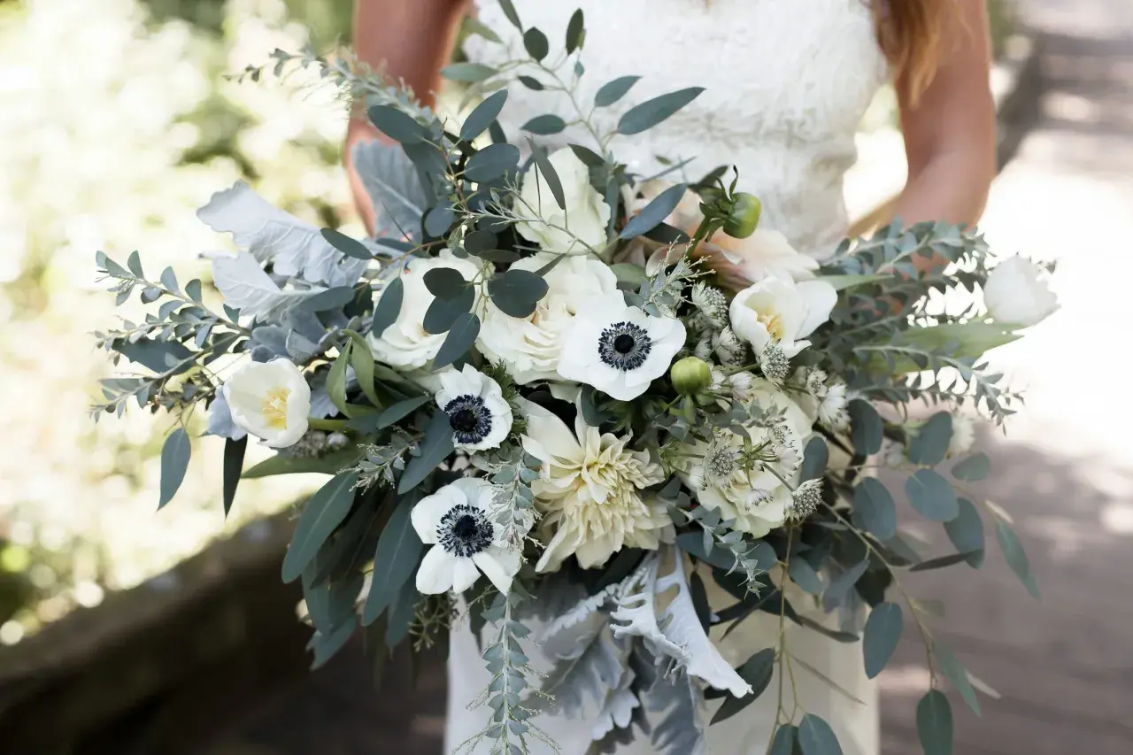Biały bukiet ślubny z anemonami, różami i eukaliptusem. Symbolika kwiatów w tym bukiecie opowiada historię o czystości i nowym początku.