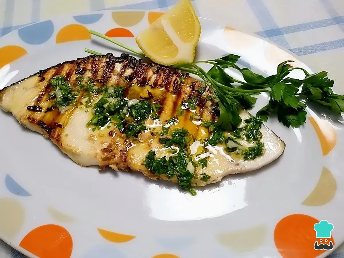 Filete de pez espada a la parrilla con perejil picado y limón.