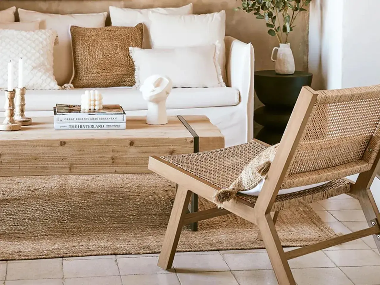 Gemütliches Wohnzimmer im boheme stil mit Rattan-Stuhl, Holztisch und Kissen.