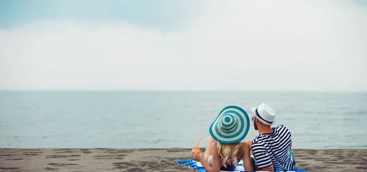 Para relaksu na plaży w Mielnie. Para w kapeluszach popija drinki, ciesząc się widokiem morza. Idealne mielno atrakcje dla dorosłych.