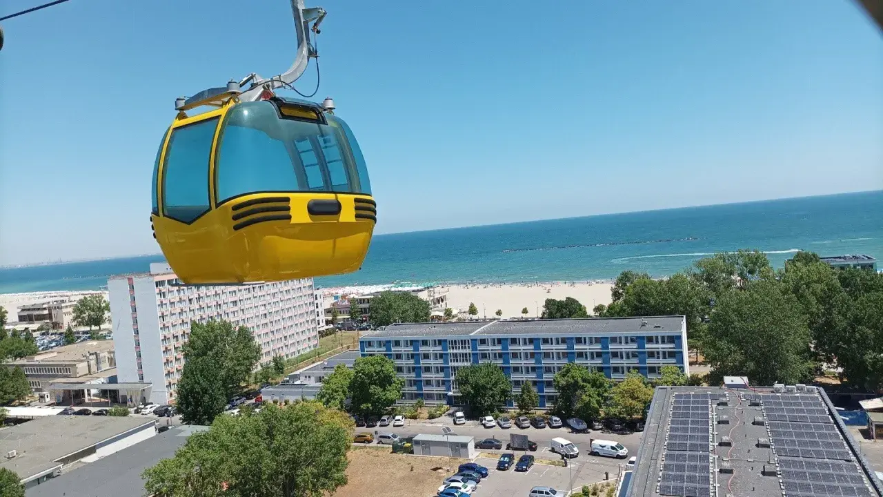 Żółta kolejka linowa nad kurortem z widokiem na piękne **konstanca plaże** i błękitne morze.