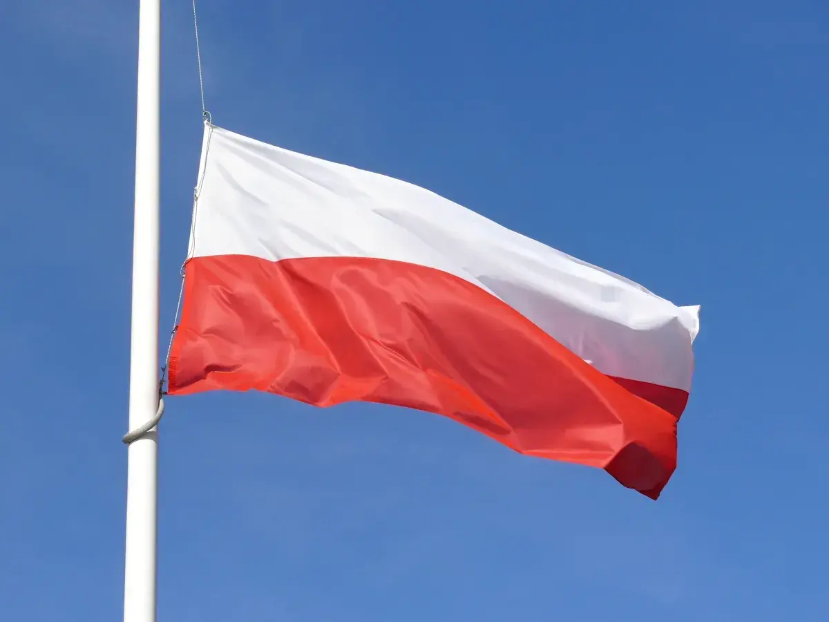 Biało-czerwona flaga Polski powiewa na maszcie na tle błękitnego nieba. Czy żałoba jest obowiązkowa?