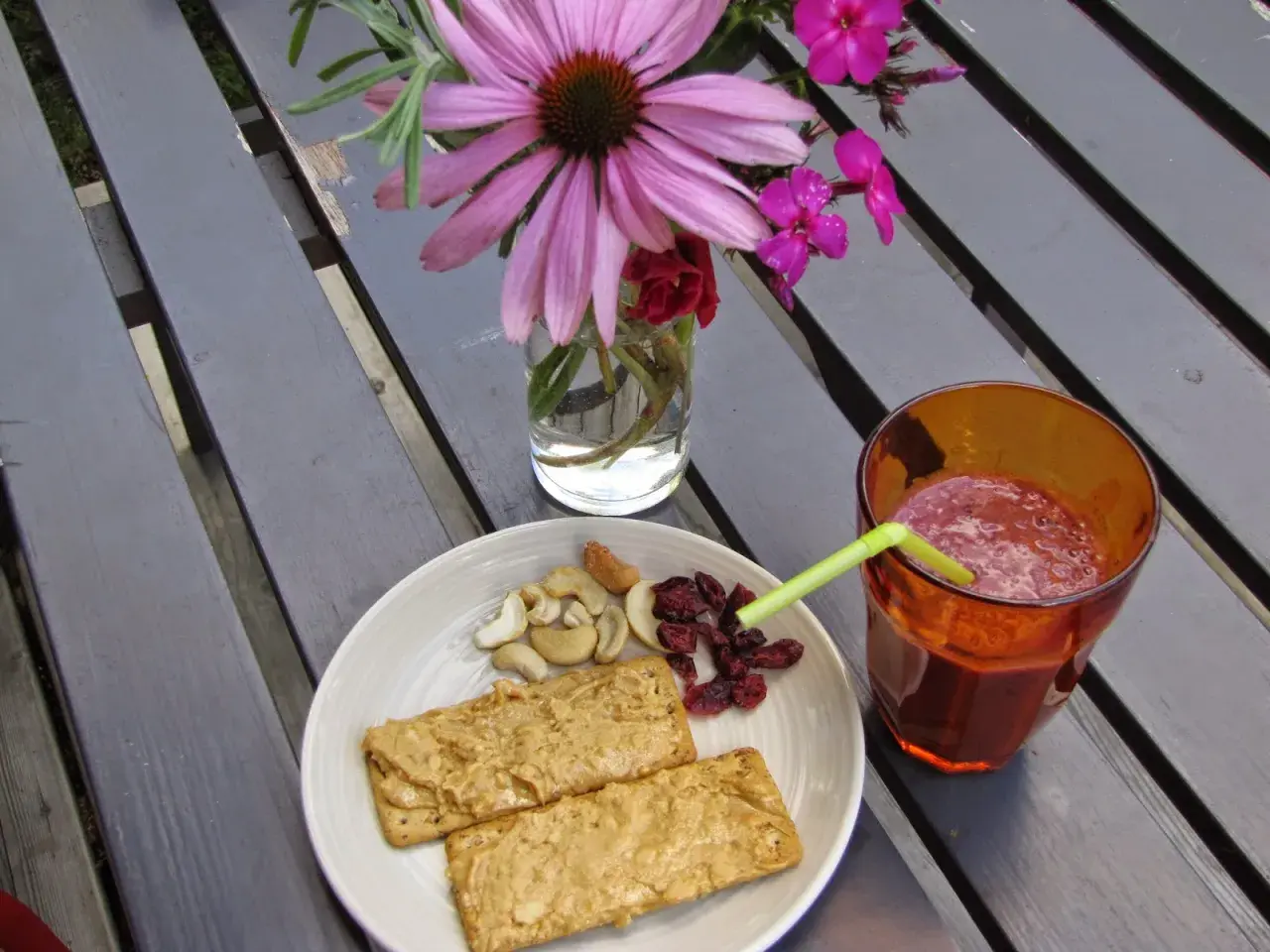 En tallrik med kex med jordnötssmör, nötter och torkade tranbär, samt ett glas smoothie. Perfekt för ett snabbt och gott mellis tips.