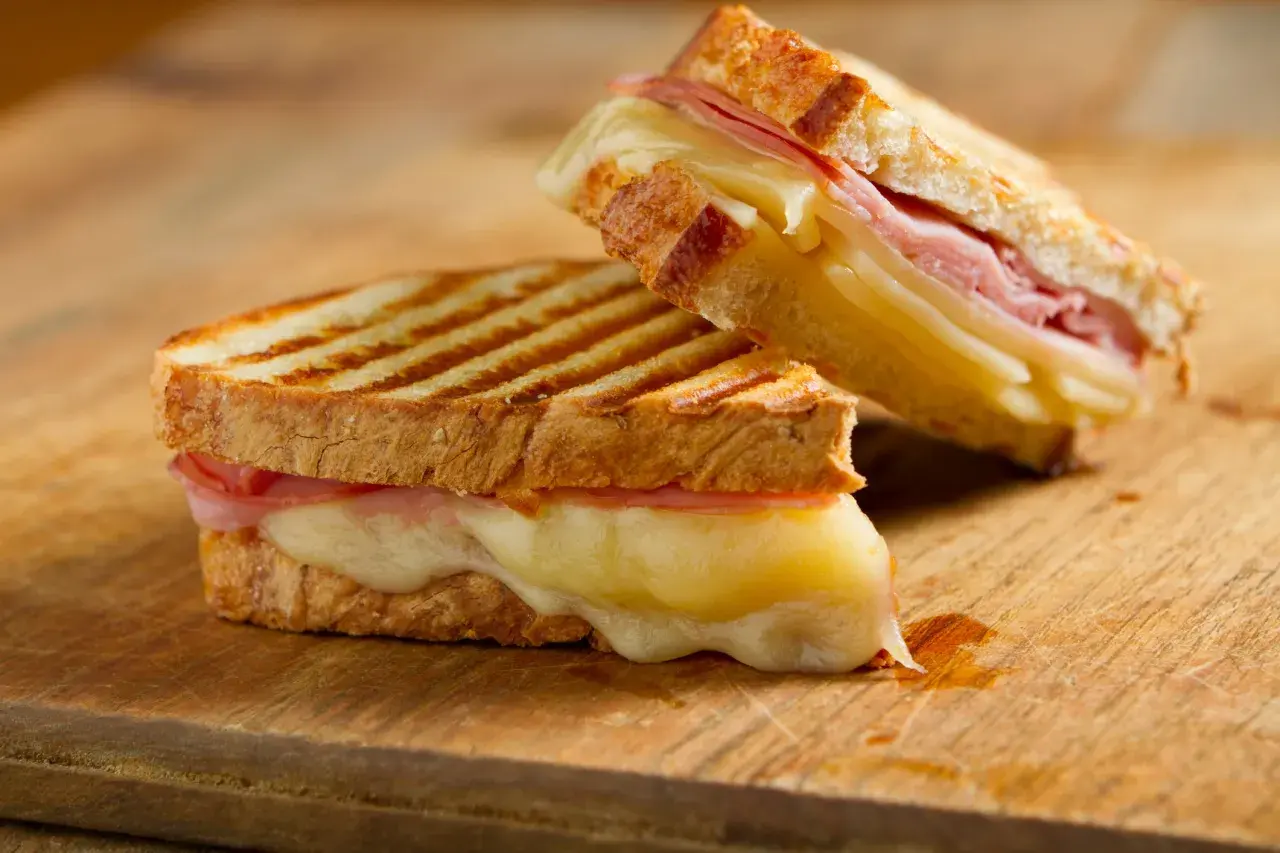 Dos deliciosos panini de queso con jamón, el queso derretido se desborda.