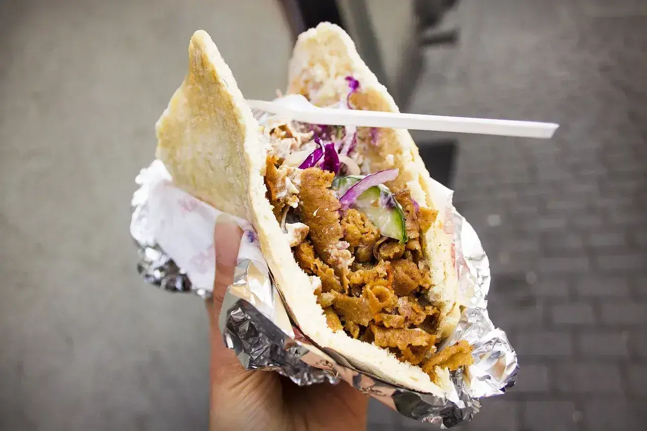 Pyszny kebab co to? Mięso, warzywa i sos w bułce, zawinięte w folię. Idealny na szybki posiłek.