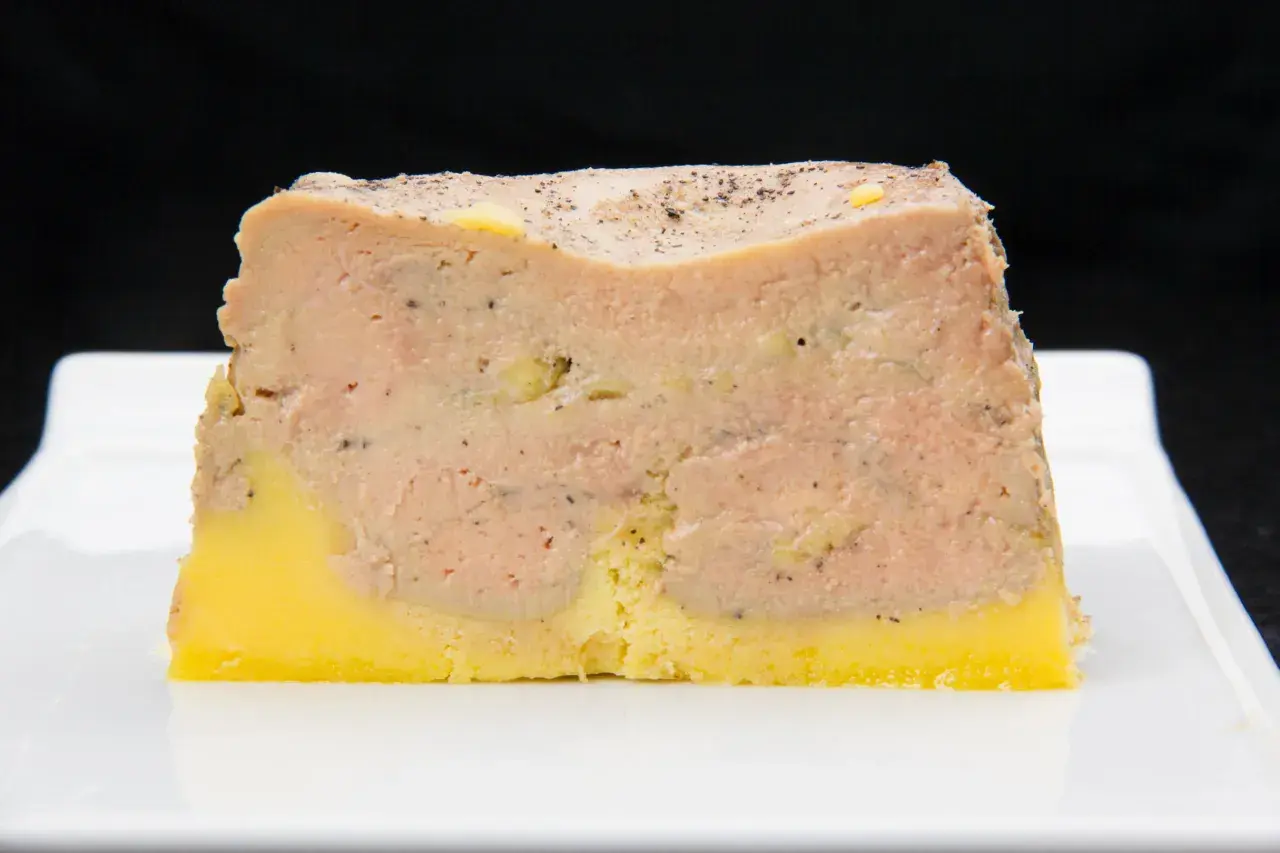 Tranche de pâté en croûte, avec une couche de viande rose et une base jaune, prête pour la cuisson.