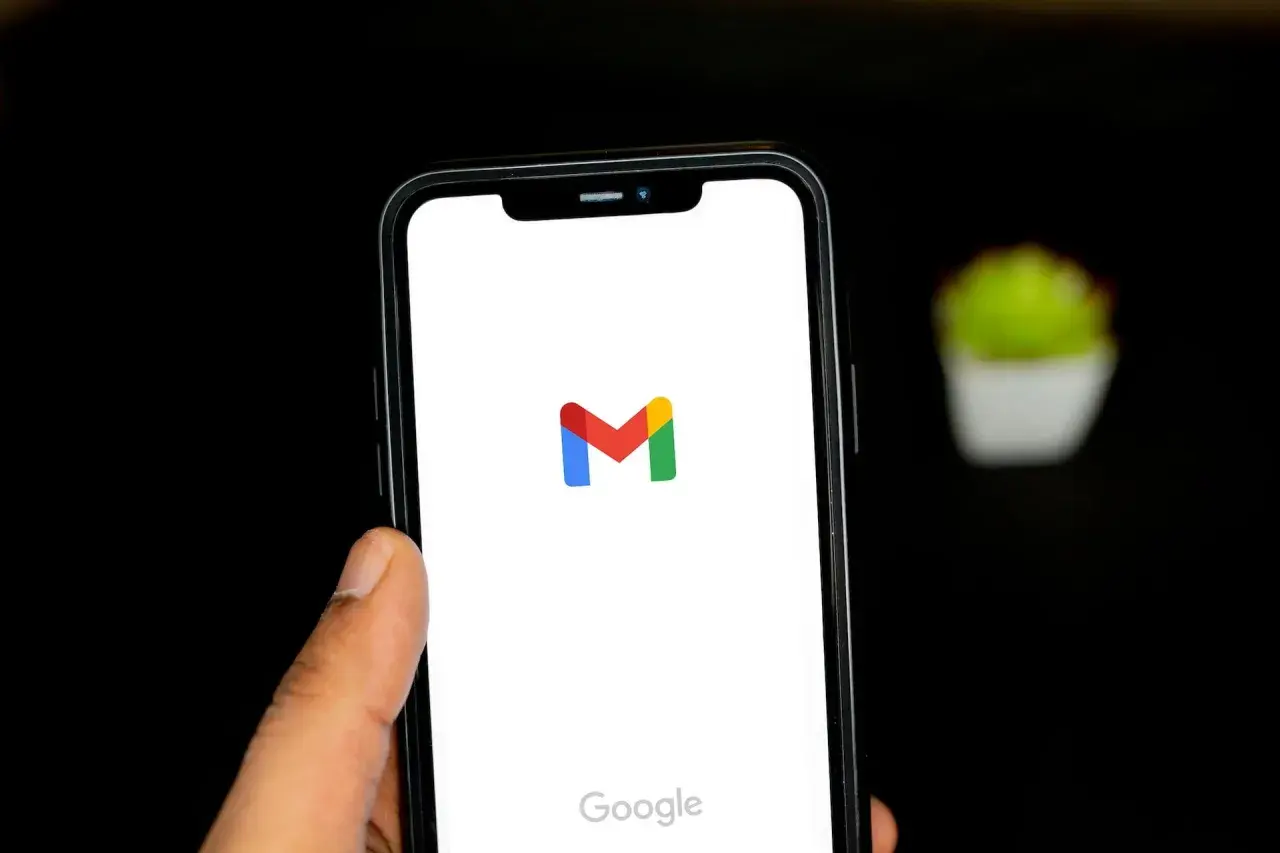 Dłoń trzyma smartfon z logo Gmail. Chcesz wiedzieć, jak wylogować się z Gmail? Ten obrazek pokazuje ekran startowy aplikacji.