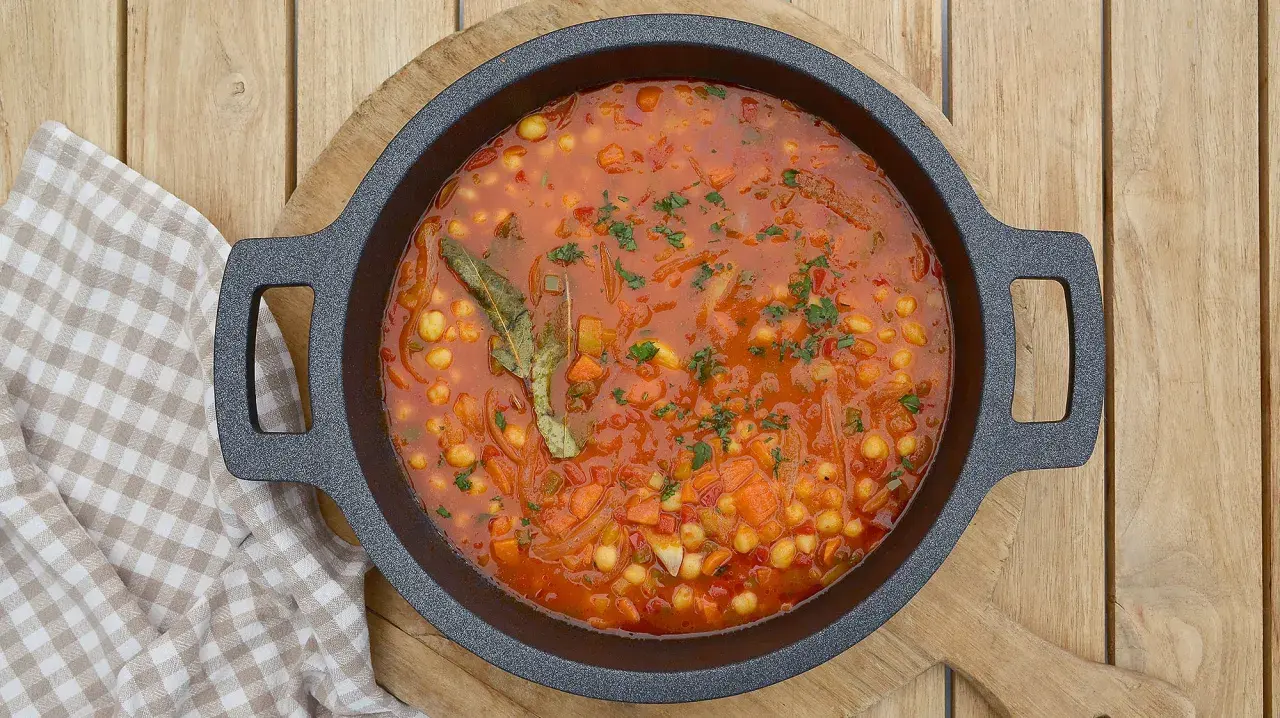 Un plato humeante de garbanzos con verduras, lleno de zanahoria, cebolla y especias, listo para ser disfrutado.
