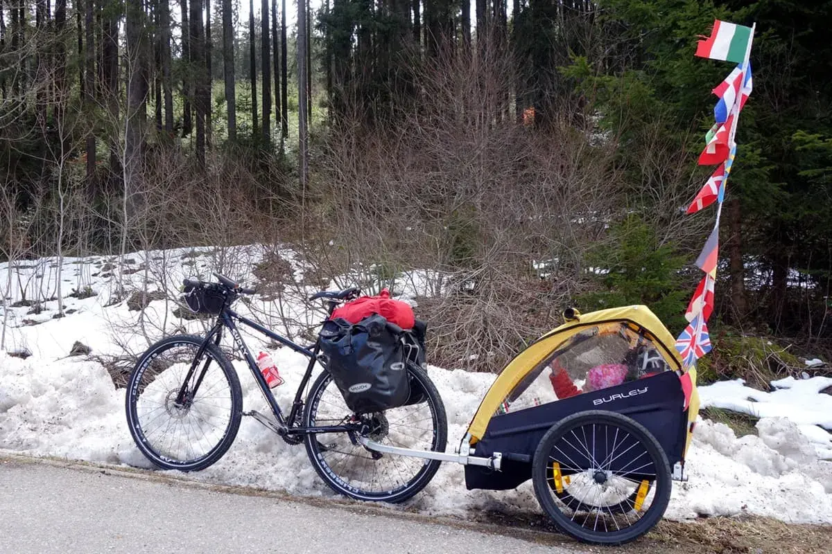 Bicicletta con rimorchio per bambini, pronta per vacanze in bici con bambini, con bandierine internazionali.