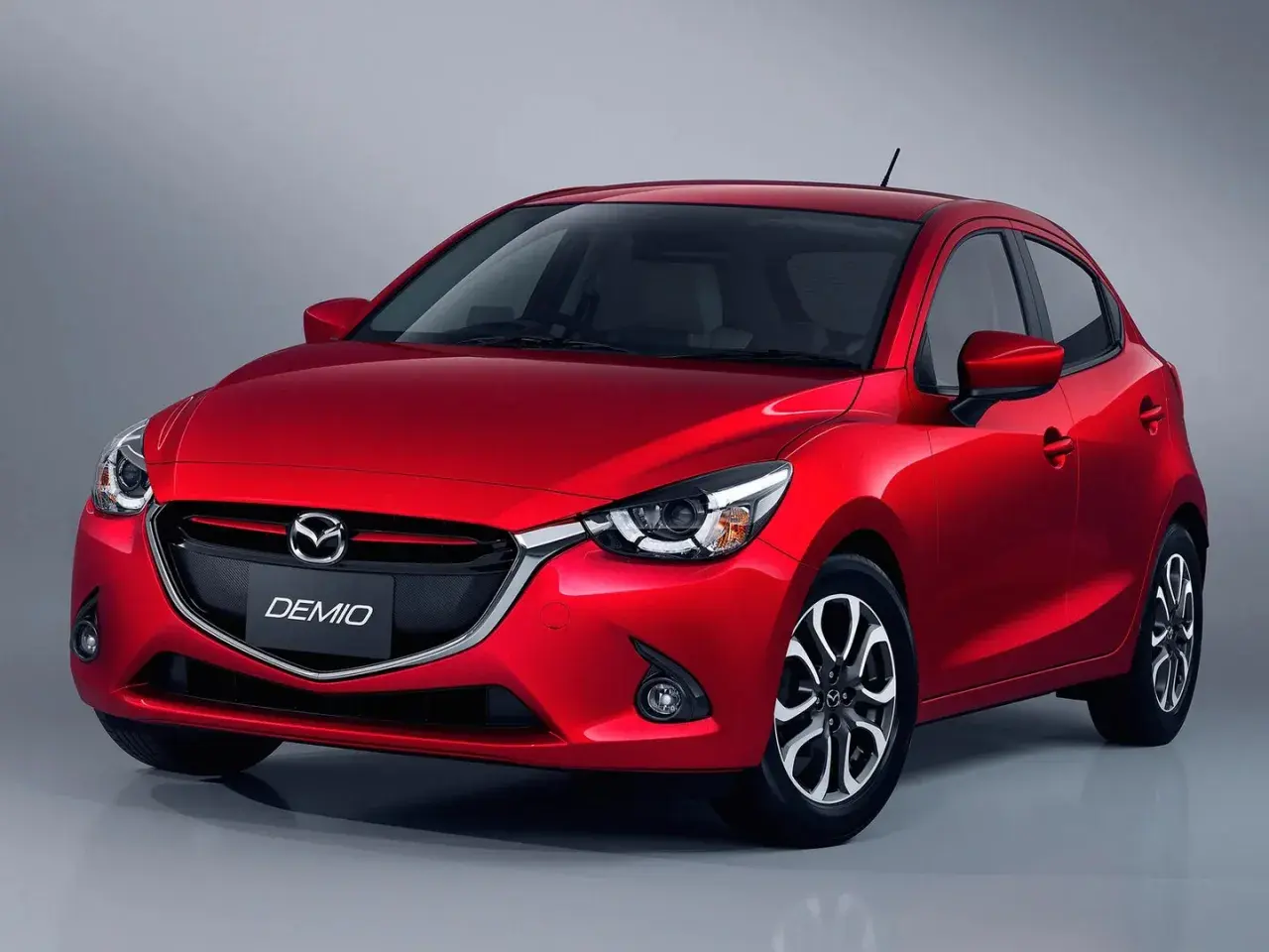 Czerwona Mazda Demio z eleganckim przodem i charakterystycznym grillem.