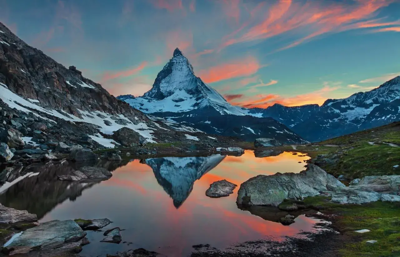 Zachód słońca nad jeziorem z odbiciem Matterhornu. Widok na wejście na Matterhorn, ośnieżone szczyty i malownicze niebo.