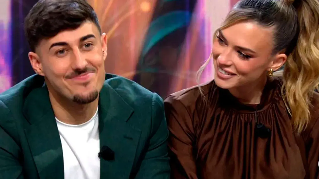 Almudena y Borja, sonriendo y mirando hacia un lado. Él lleva una chaqueta verde y ella un vestido marrón.