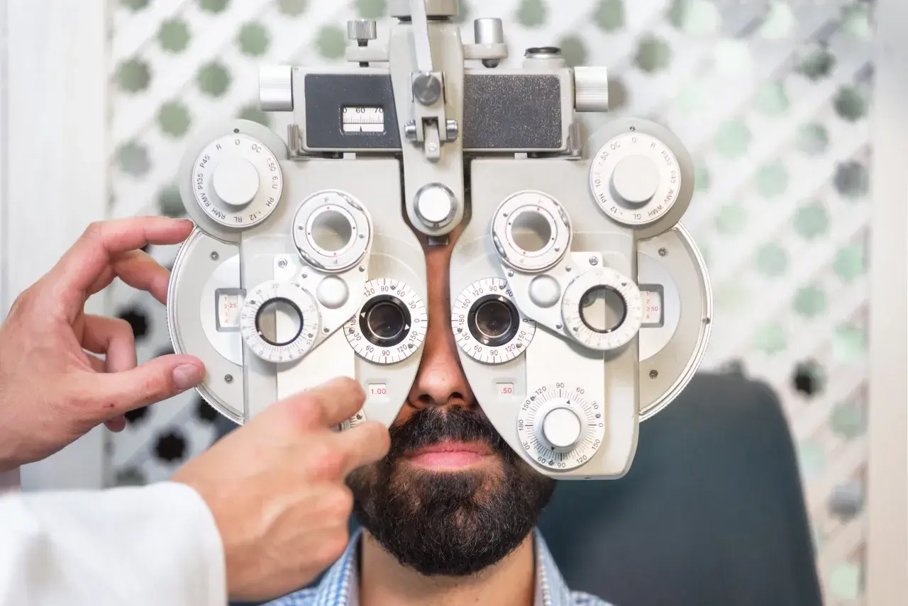 Optometrysta to specjalista od wzroku. Mężczyzna z brodą przechodzi badanie wzroku na foropterze.