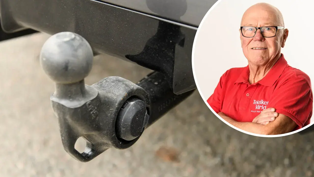 En man i röd tröja med texten "Tekniker Värld" ler. Bredvid syns en dragkrok, kanske för en besiktning.