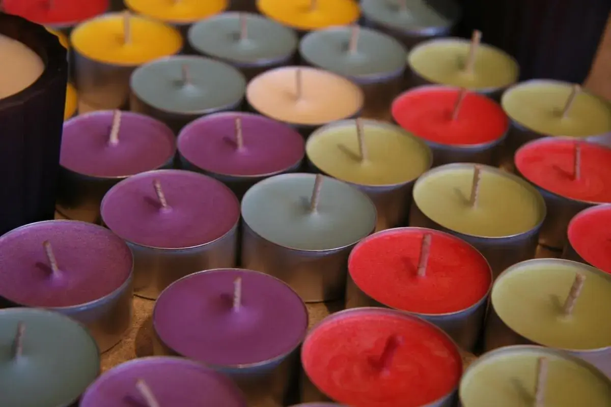 Un surtido de velas no tóxicas de colores vibrantes, dispuestas en filas.