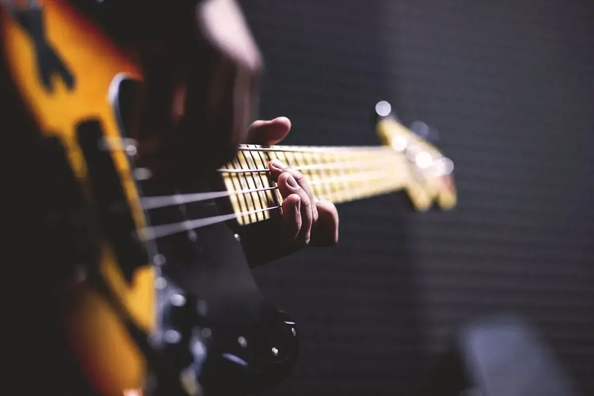 Main d'un bassiste jouant sur une guitare électrique. Parfait pour un texte pour annoncer la sortie d'un single.