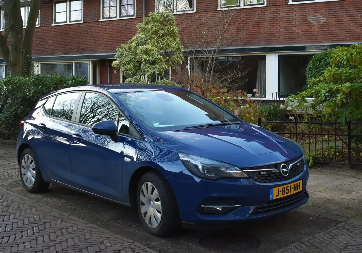Niebieski Opel Astra K 1.6 CDTI zaparkowany przed domem z cegły.