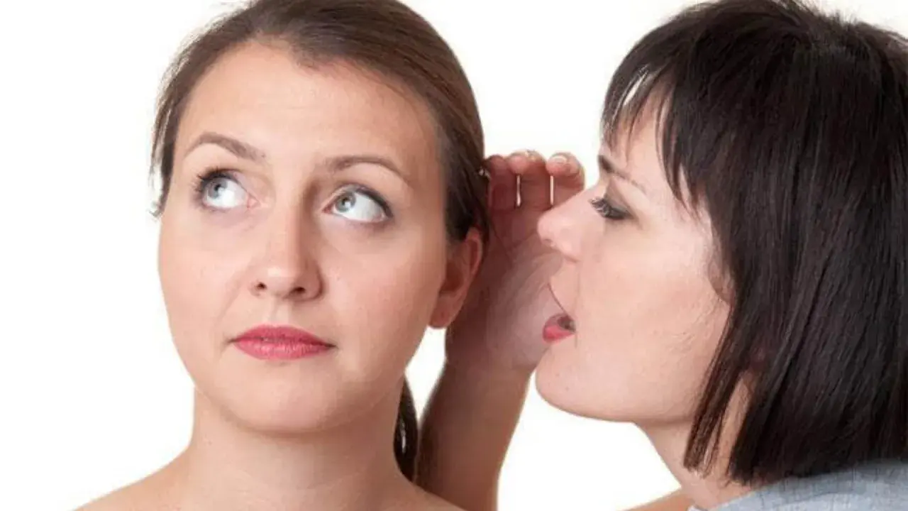 Two women, one whispering into the other's ear.